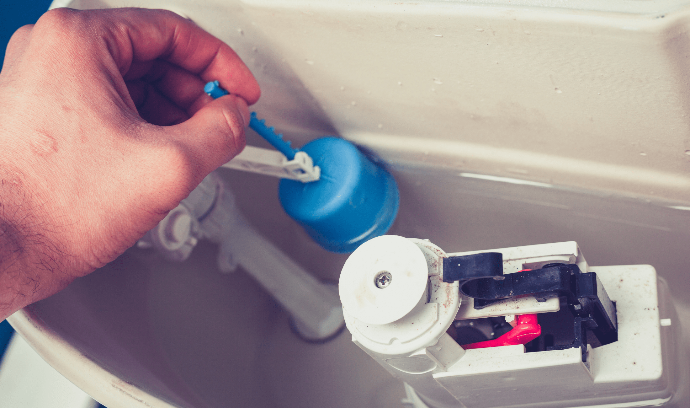 A person reaching into a toilet tank to adjust the valve.