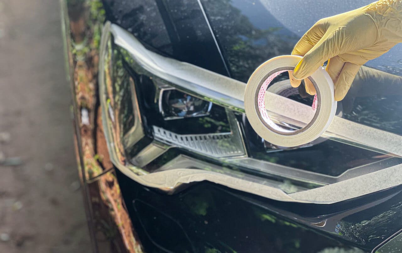 Applying masking tape around car headlights