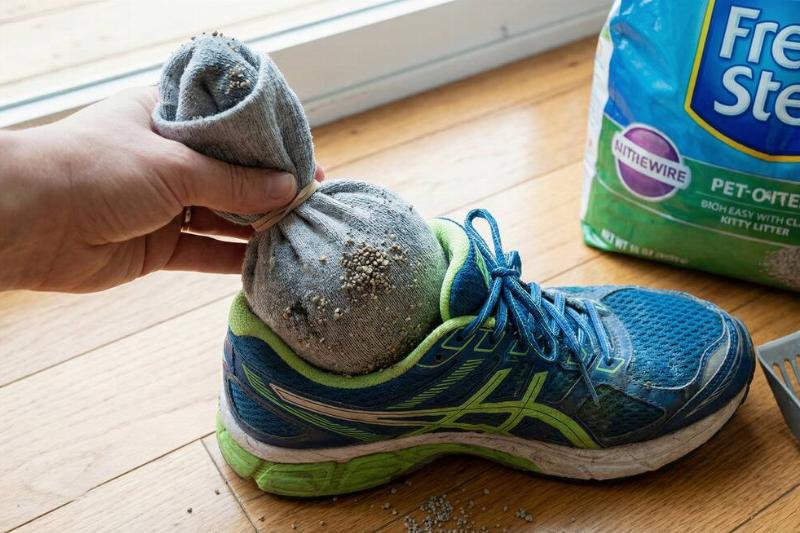 A hand putting a sock full of kitty litter into a running shoe.