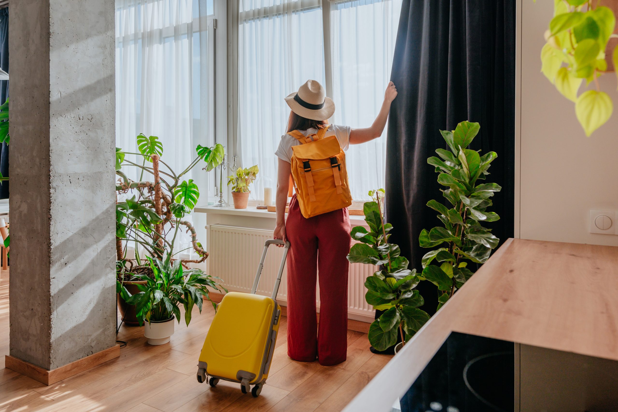 Woman looking out a window with houseplants nearby