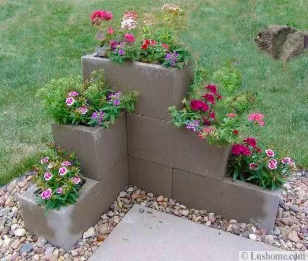 L-shaped tiered concrete block planter with colorful flowers