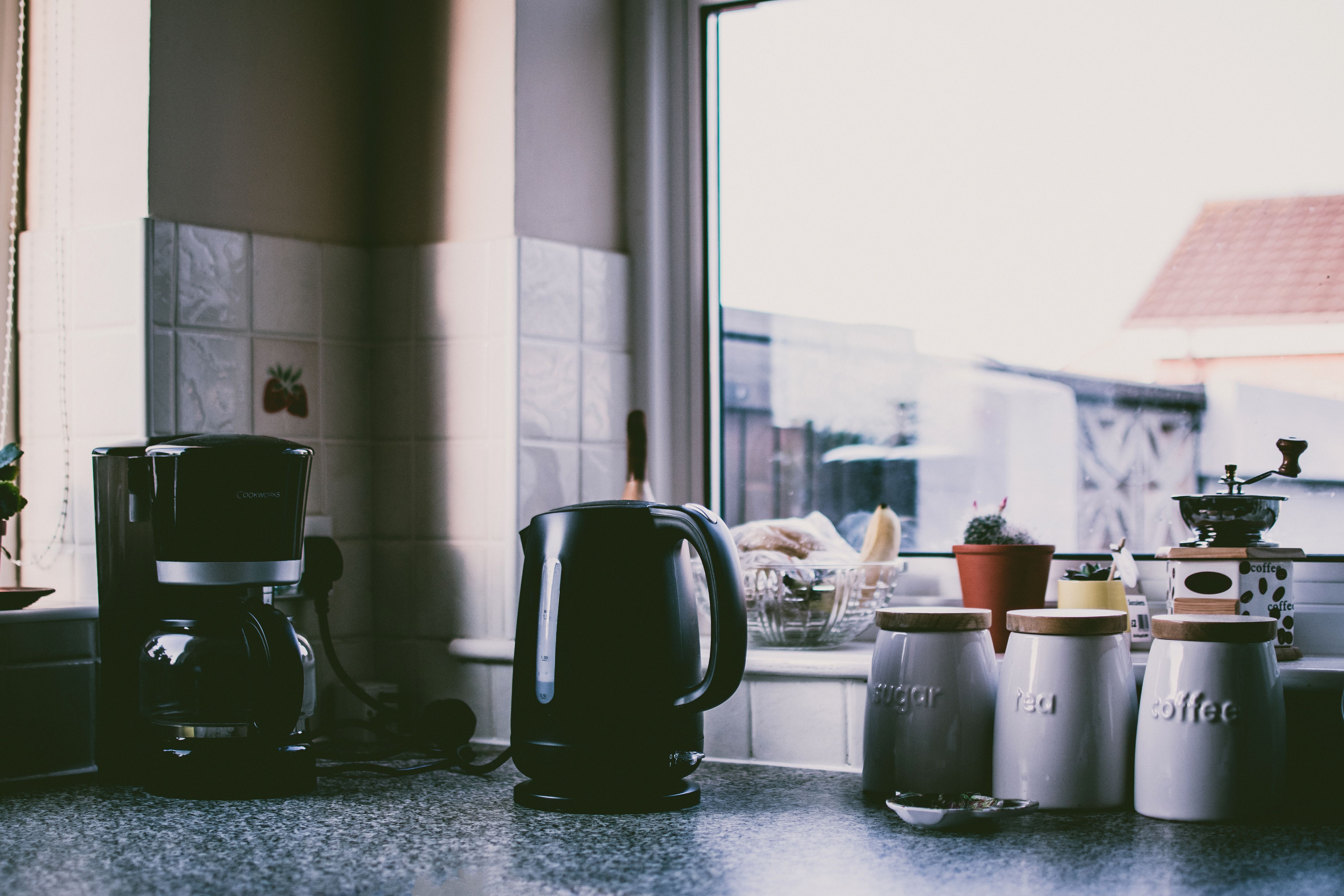 A kitchen with a coffee maker and kettle on the counter