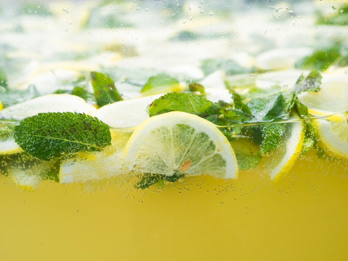 A glass of lemon water with mint leaves and ice