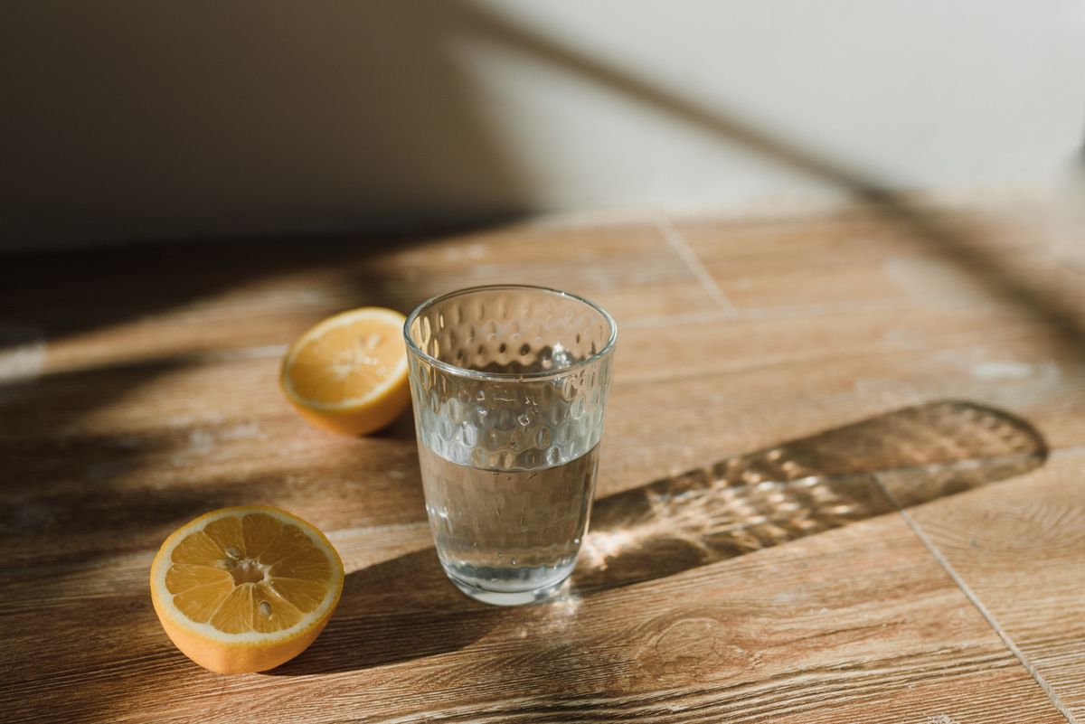 A morning glass of lemon water next to fresh lemons