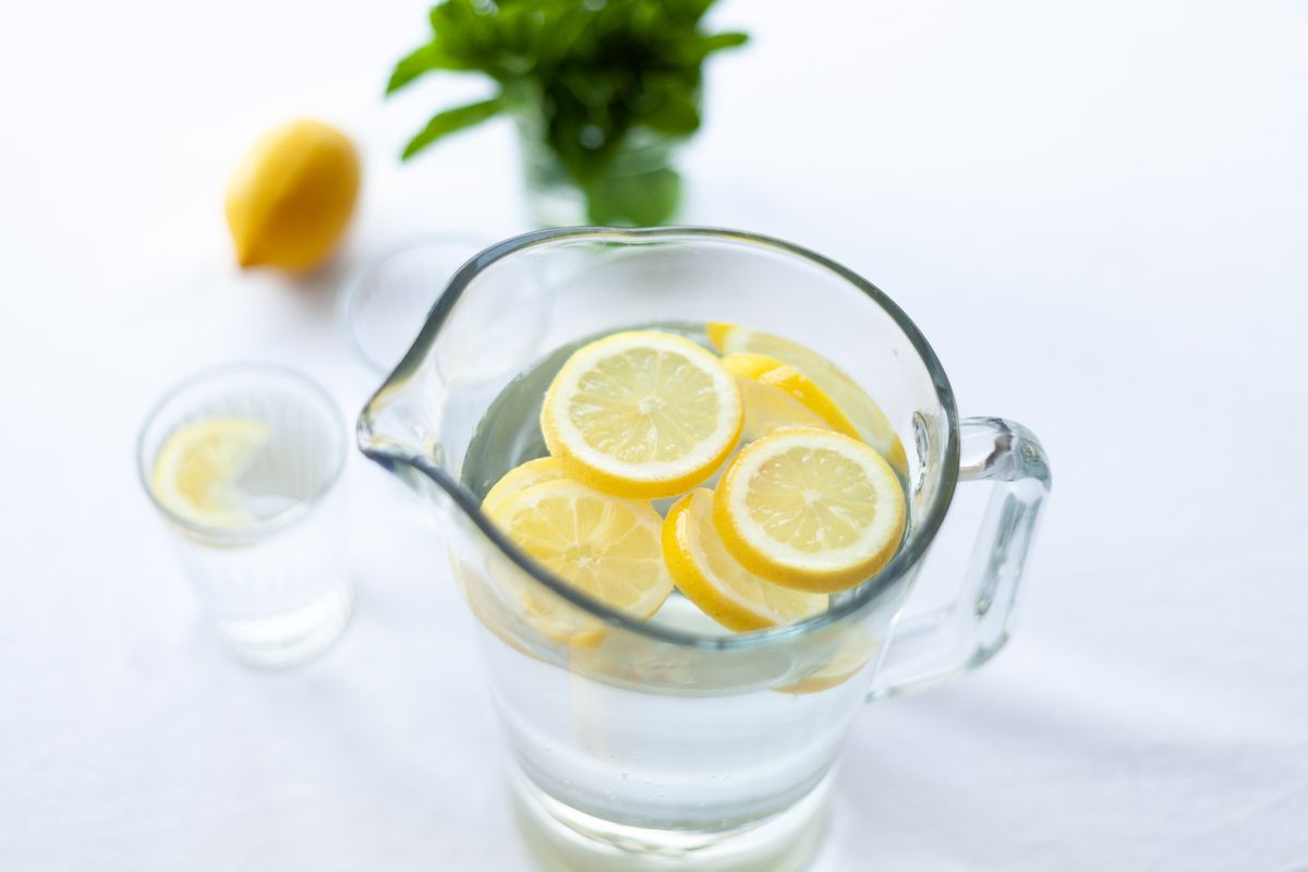 A clear glass of water with lemons on a bright table