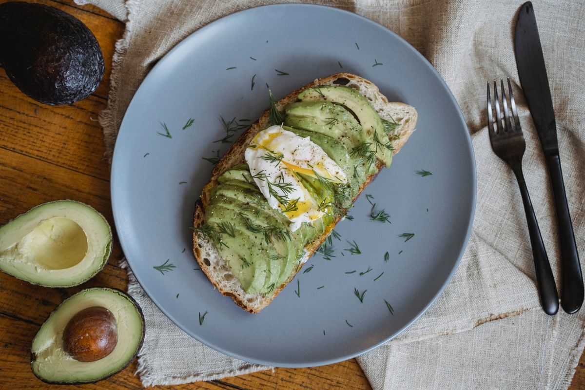 Avocado toast topped with seeds on a simple plate