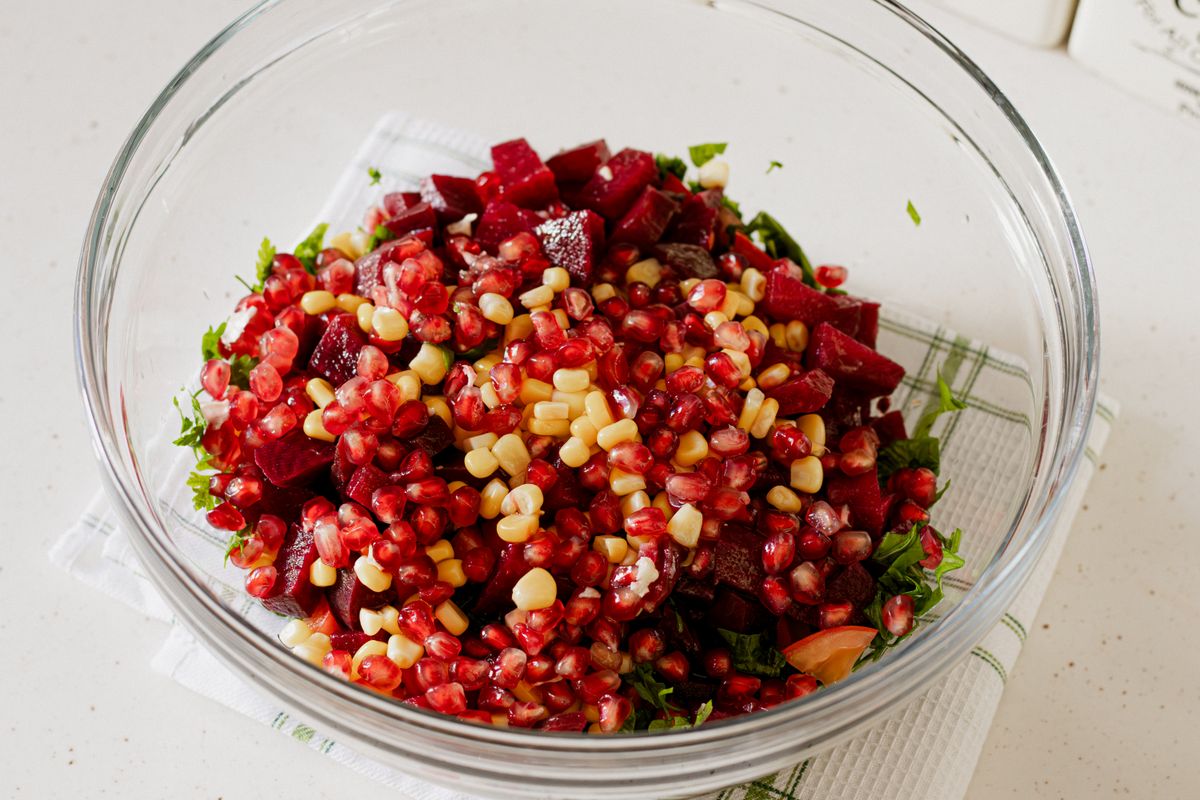A bowl of beet salad with greens and sliced vegetables