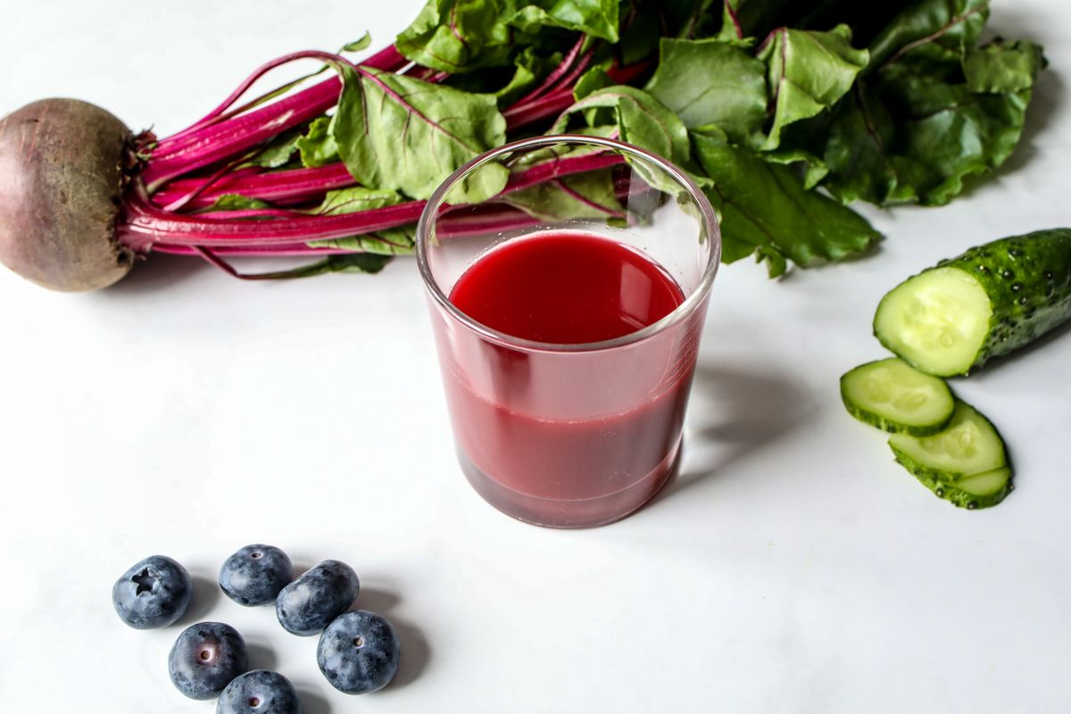 A glass of beet juice beside sliced beetroot