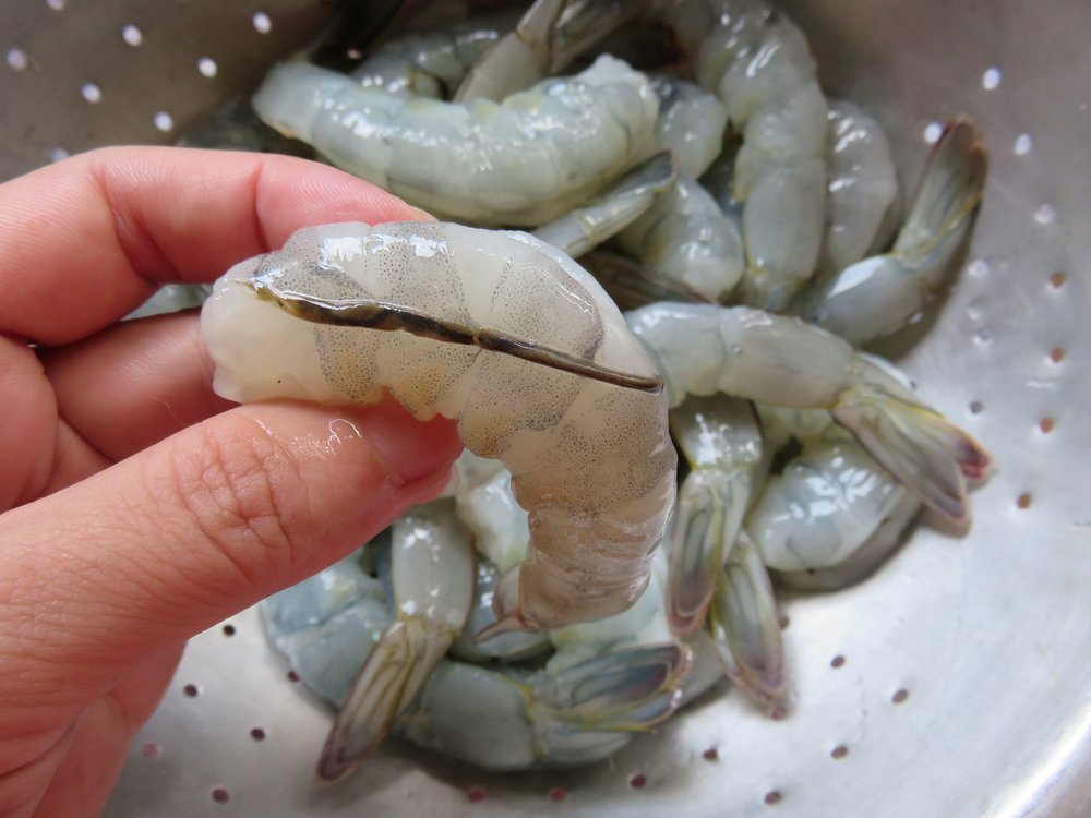 Making an incision along the shrimp's back to remove the black line, the digestive tract, before cooking. Shrimp can be used in salads, scampi, or skewers.