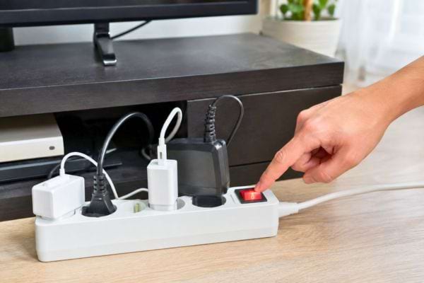 Hand turning off a power strip underneath the TV stand.