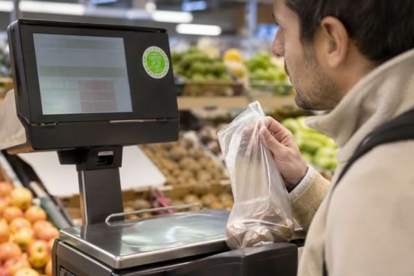Customer checking the green inspection sticker on a fresh produce scale.