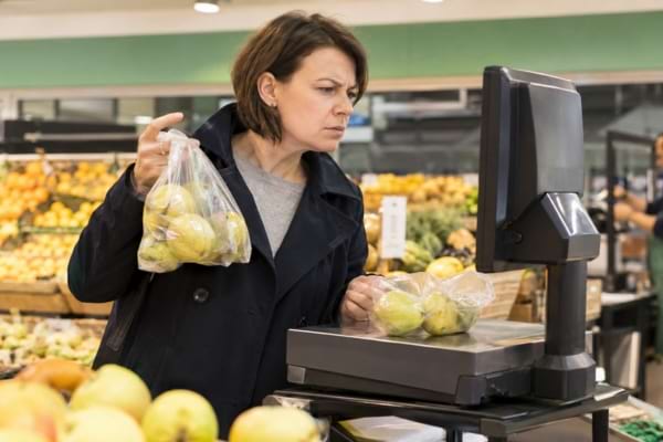 Customer looking puzzled as she reweighs her fruits in the supermarket.