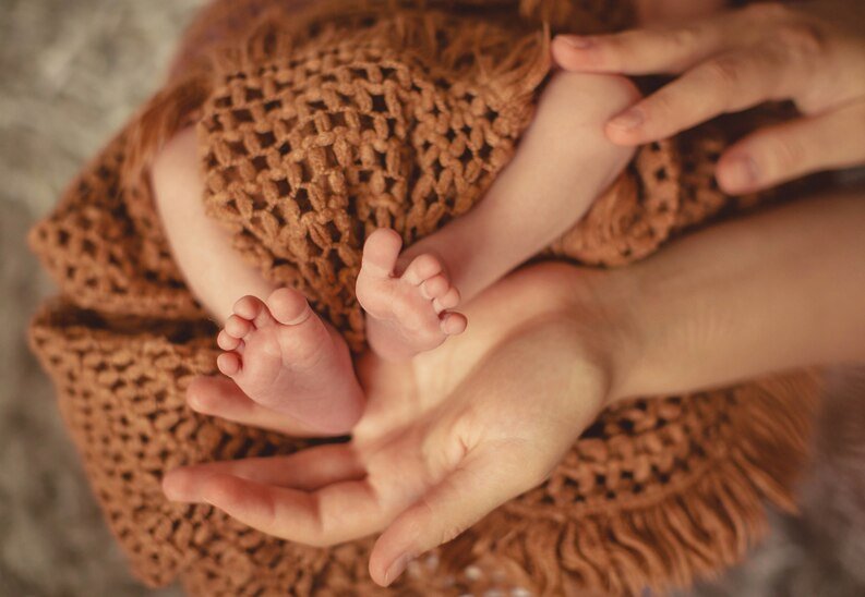 A mother's hands holding a baby's little legs